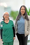 Two women in healthcare attire standing together.