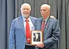 Two men with a framed photo at a recognition event.