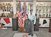Veteran holding a military jacket in a trophy display area.