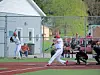 Baseball player swings at a pitch during a game.