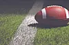 A football on green turf next to a white line.
