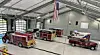 Interior of a fire station with several fire trucks parked.