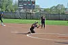 Softball player crouches to catch a ball on the field.
