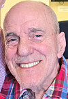 Elderly man smiling in a plaid shirt.