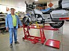Mechanic with motorcycle on a lift in a workshop.