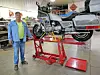 Mechanic with motorcycle on a lift in a workshop.