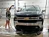 Woman washing a Chevrolet truck with a hose.
