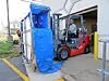 Forklift unloading blue-wrapped cargo at a warehouse entrance.