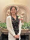 Woman smiling in front of a fountain with cherubs.