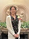 Woman smiling in front of a fountain with cherubs.