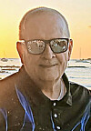 Man with sunglasses smiling at the beach during sunset.