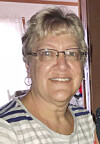 Smiling woman with glasses in a casual indoor setting.