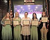 Five individuals holding scholarship certificates at an event.