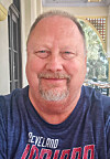 Man smiling outdoors in a Cleveland Indians shirt.