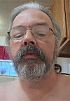 Close-up of a person with glasses and a beard in a kitchen.