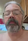 Close-up of a person with glasses and a beard in a kitchen.
