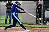 Player swings a bat at a softball in a game.