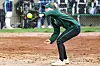 Softball player in green reaching for a ball.