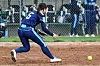 Softball player reaching for a ball on the field.