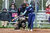 Softball player swinging bat with catcher in position.