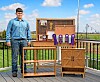 Young woodworker with award-winning wooden furniture outdoors.