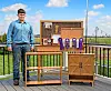 Young woodworker with award-winning wooden furniture outdoors.