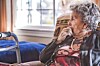 Elderly woman sitting in a chair, looking out the window.