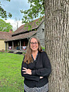 Woman standing next to a tree in front of a historic building.