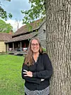 Woman standing next to a tree in front of a historic building.