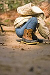 Child crouching on sandy ground in a forest.