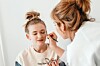 Makeup artist applying makeup to a girl in a studio.