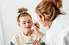 Makeup artist applying makeup to a girl in a studio.