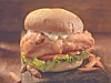 Close-up of a fried chicken sandwich with lettuce and tomato.