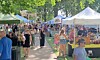 A busy community market with tents and people browsing.
