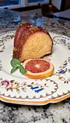 Slice of cake with orange slice and mint on a decorative plate.