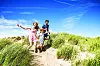 Family running through grass on a sunny day.