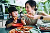 Woman and girl enjoying pizza together at a table.