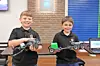 Two boys holding robotics projects in a classroom.