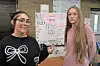 Two students posing in front of a poster at a school event.