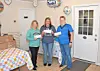 Three women holding checks in a decorated room.