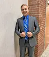 Young man in a suit smiling in a hallway