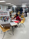 People discussing at tables in a library during a financial literacy event.