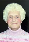 Close-up portrait of an elderly woman with white hair wearing a pink sweater.