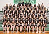 Large gymnastics team posing in rows on bleachers inside a gym with a green HONORATION sign behind them.