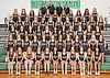 Large gymnastics team posing in rows on bleachers inside a gym with a green HONORATION sign behind them.