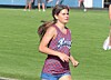 Athlete running on a green grass field wearing a blue and red patterned uniform.