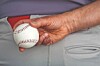 Close-up of a hand holding a baseball near a person’s waistband.