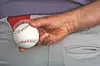 Close-up of a hand holding a baseball near a person’s waistband.