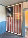 Large framed American flag displayed on an interior wall beside an open doorway.