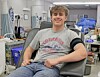 Young man sitting in a medical treatment chair in a clinic with medical equipment behind him.